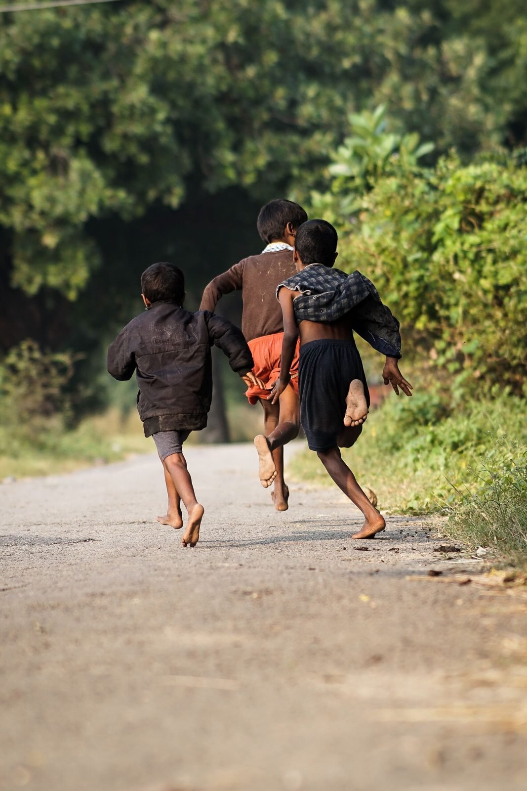 Tres niños corriendo por un camino rural