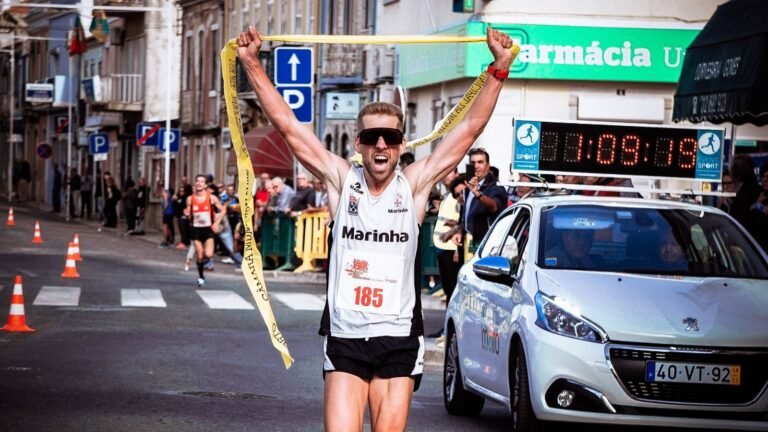 Corredor cruzando la meta de un maratón con los brazos en alto