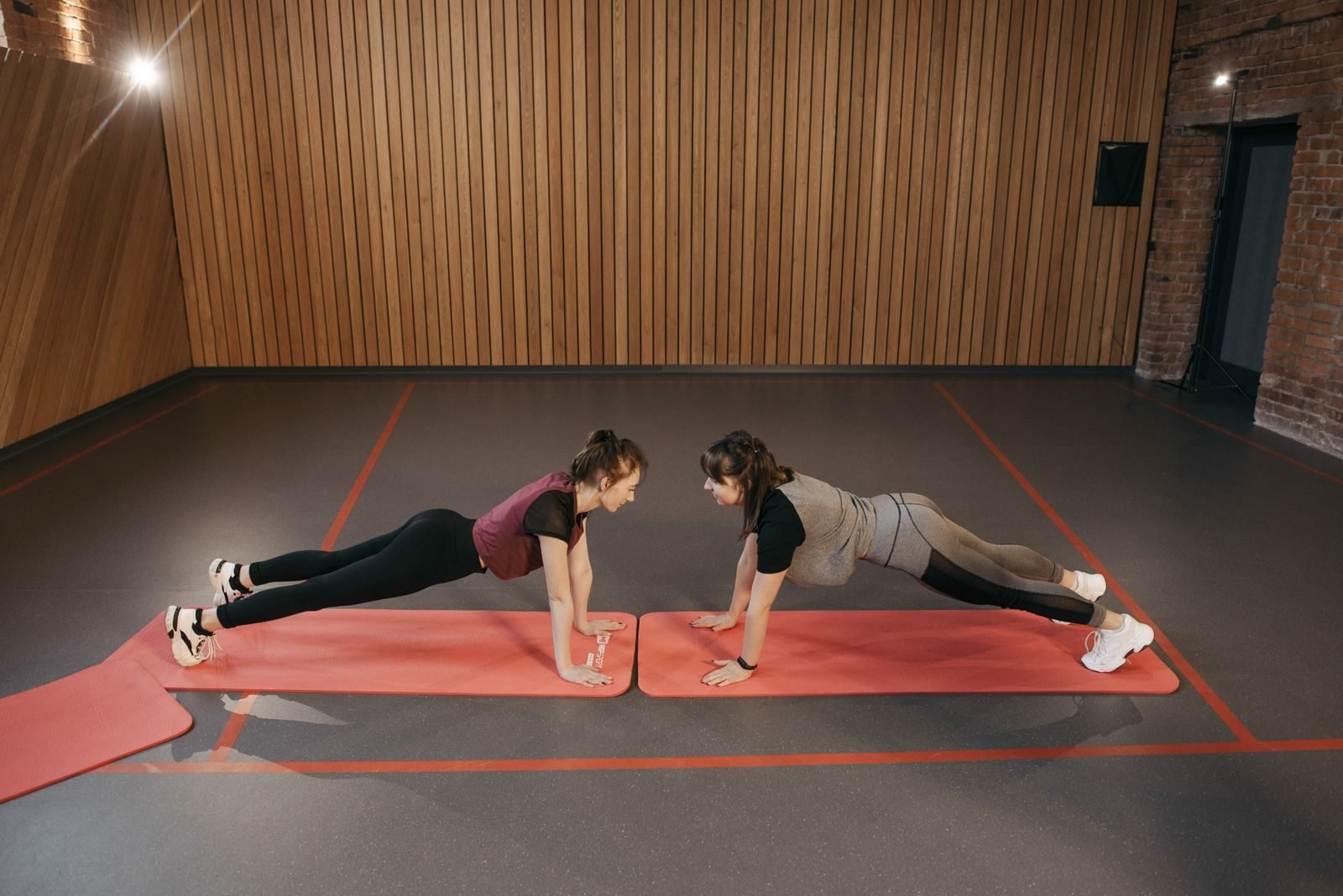 Dos mujeres haciendo plancha en esterillas del gimnasio