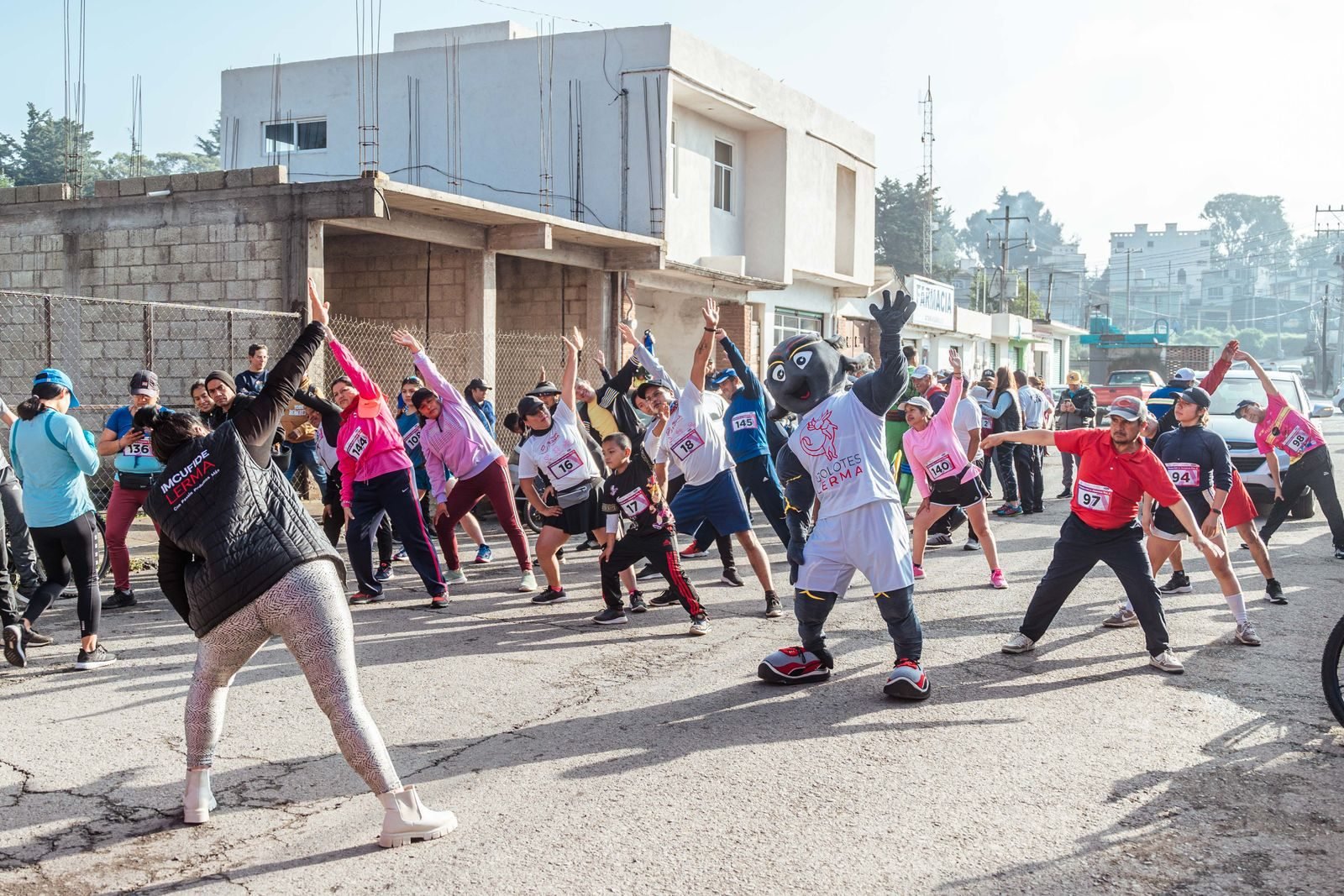Group of runners stretching together on a street before a race