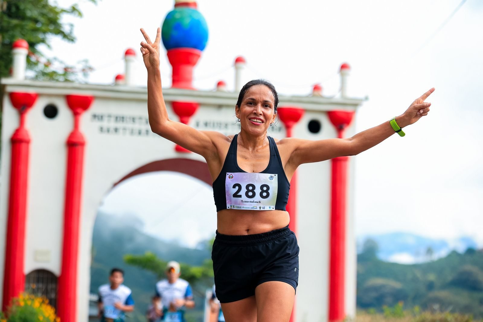 Corredora entrando en meta con los brazos en alto tras batir la marca que le daba el predictor de marcas