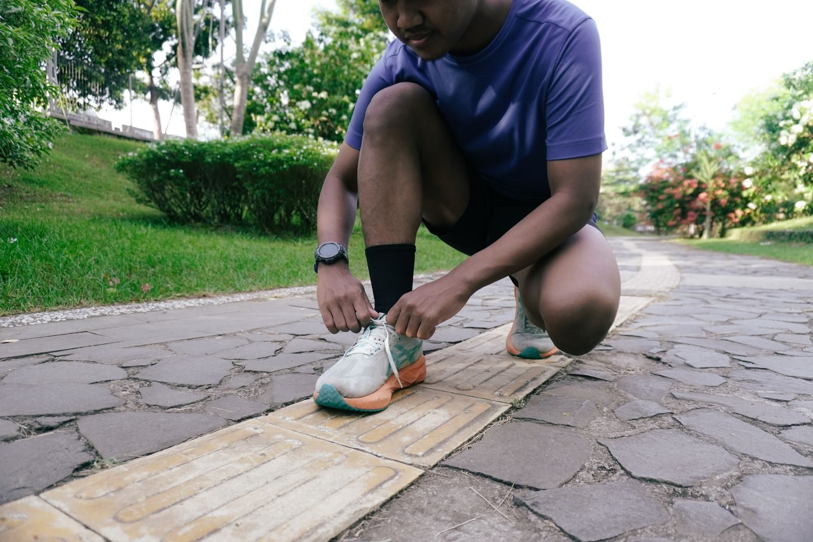 Corredor atándose los cordones antes de salir a correr por un parque