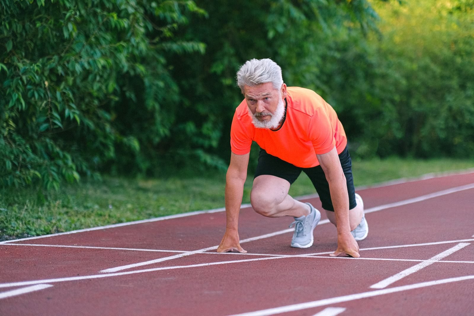 Corredor veterano preparado para salir en una pista de atletismo, regalos para corredores mayores