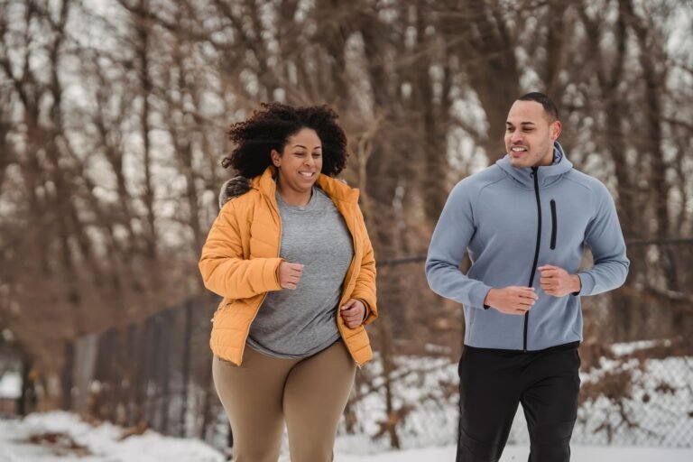 Pareja corriendo en la nieve con ropa de invierno, idea de regalos para runners