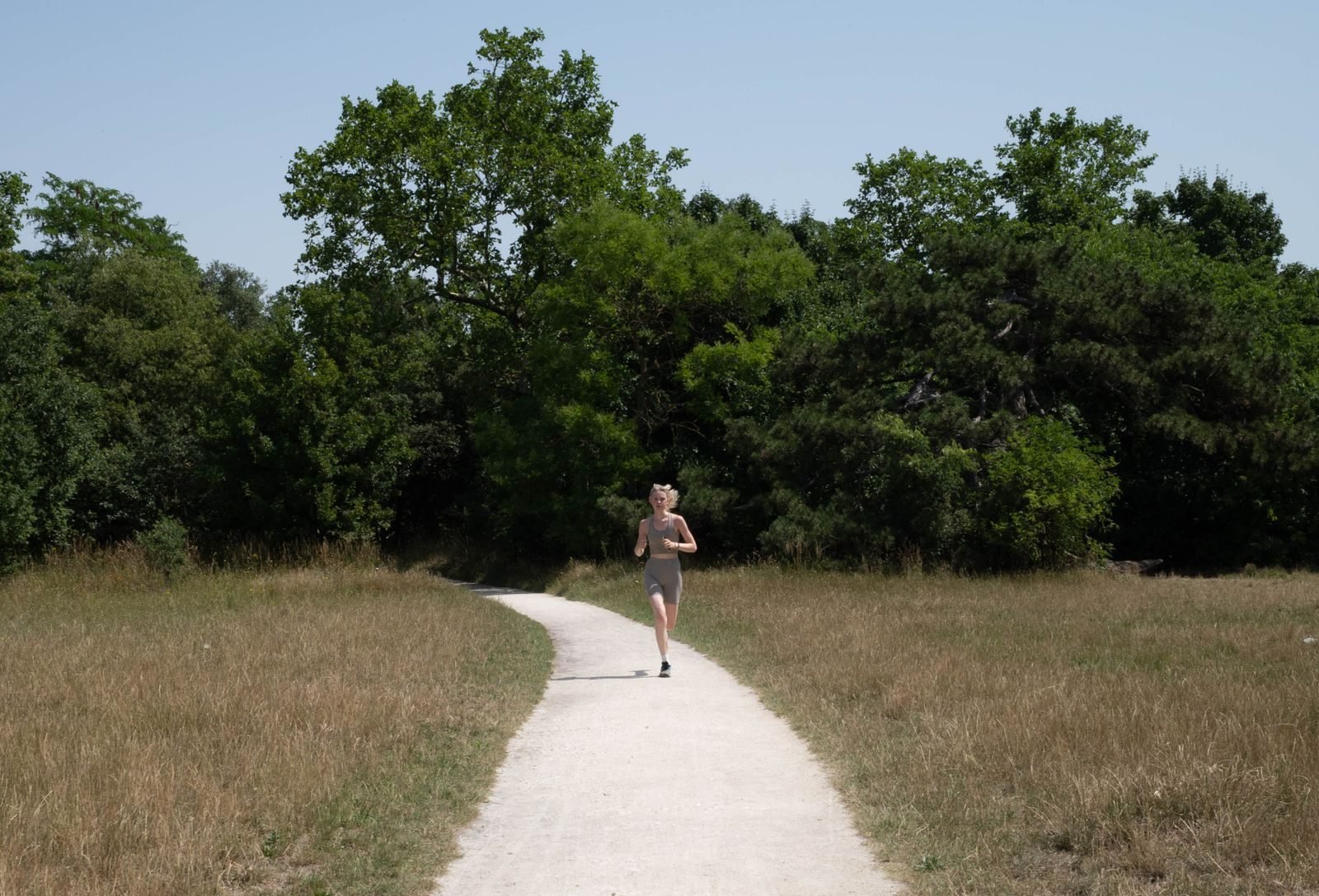 Persona corriendo por un sendero del bosque al sol, cómo respirar al correr