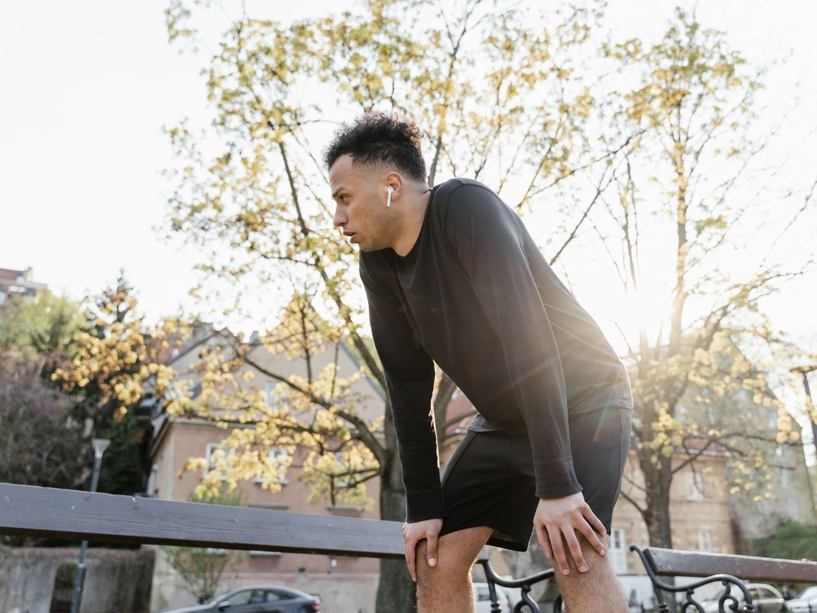 Man pausing during a run in a sunny park