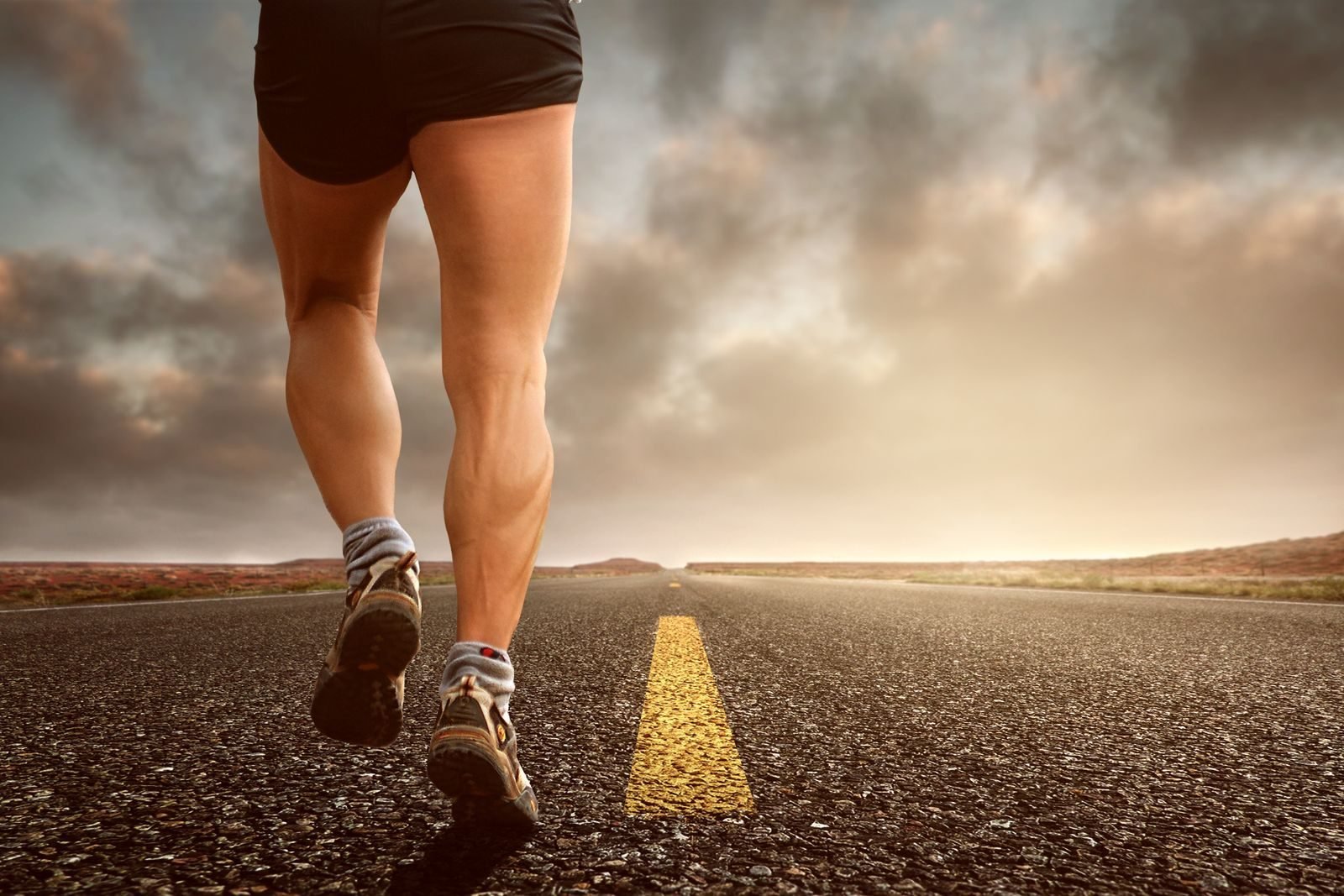 Legs of a runner on the road at sunset