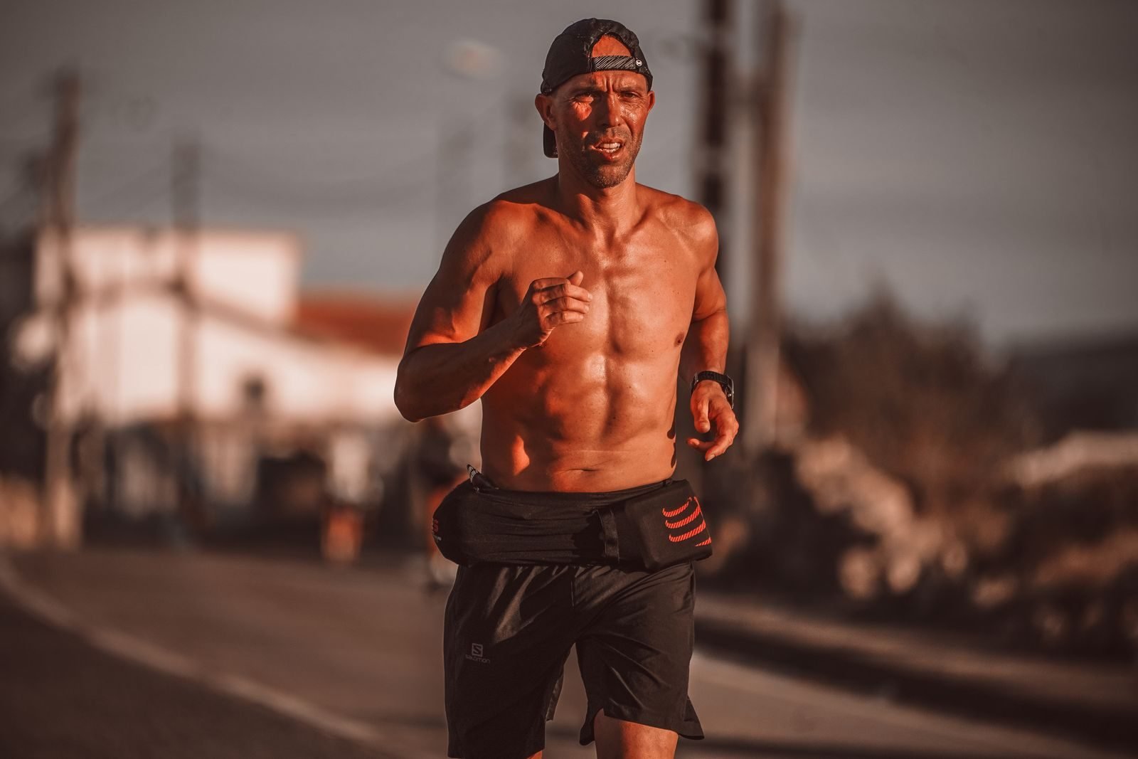 Hombre corriendo al aire libre en un día soleado, ajustando el ritmo al correr con calor