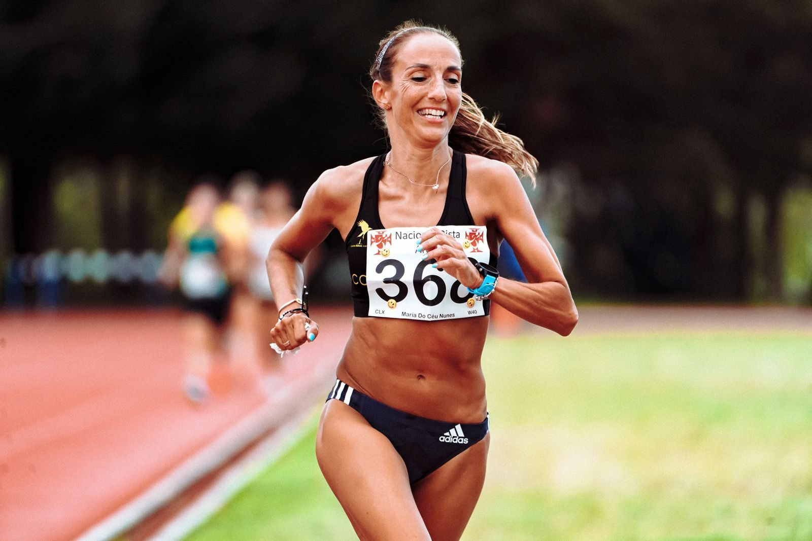 Atleta sonriente corriendo en pista durante una competición