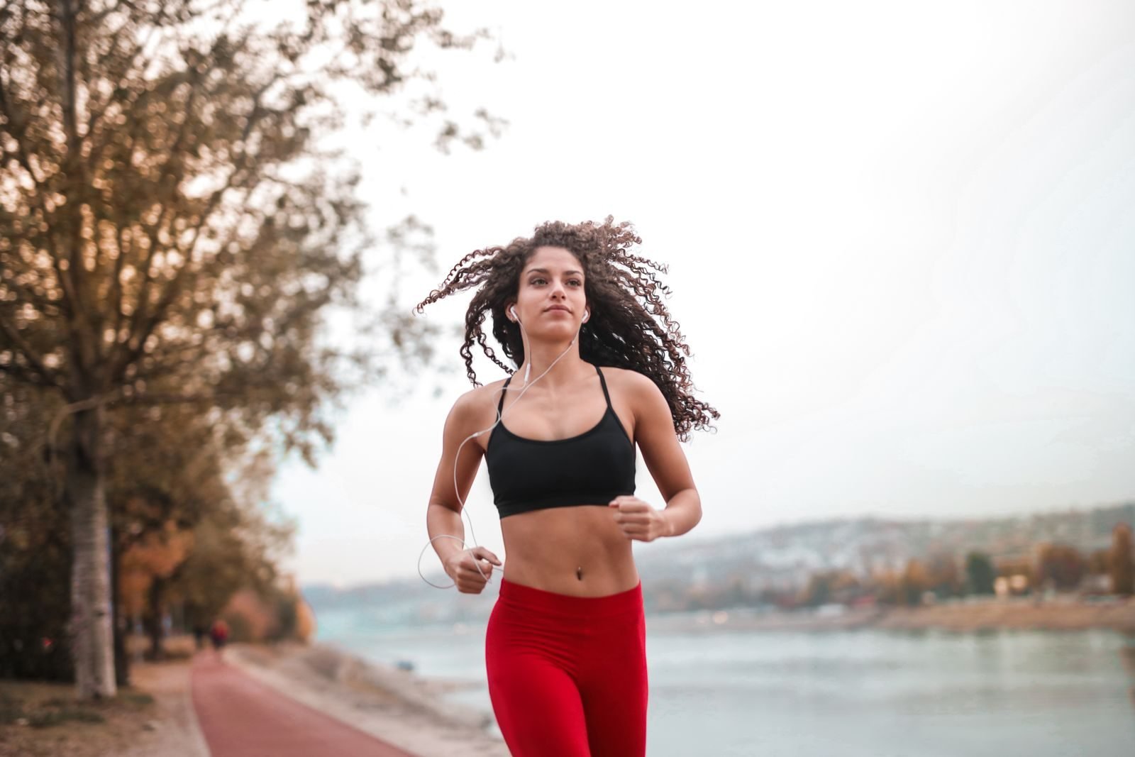 Mujer corriendo a ritmo suave por un paseo junto al río durante su tirada larga