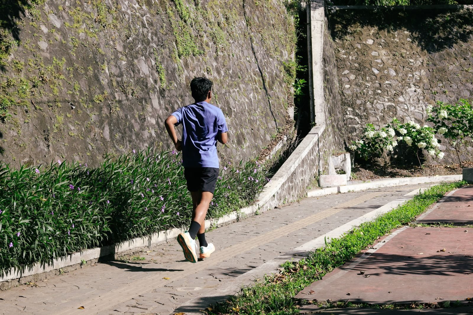 Joven corriendo por un camino soleado rodeado de vegetación
