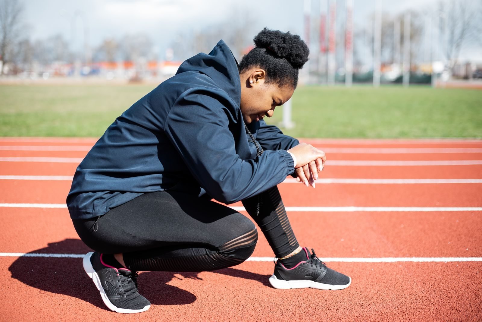 Runner crouching on the track during recovery between critical power intervals