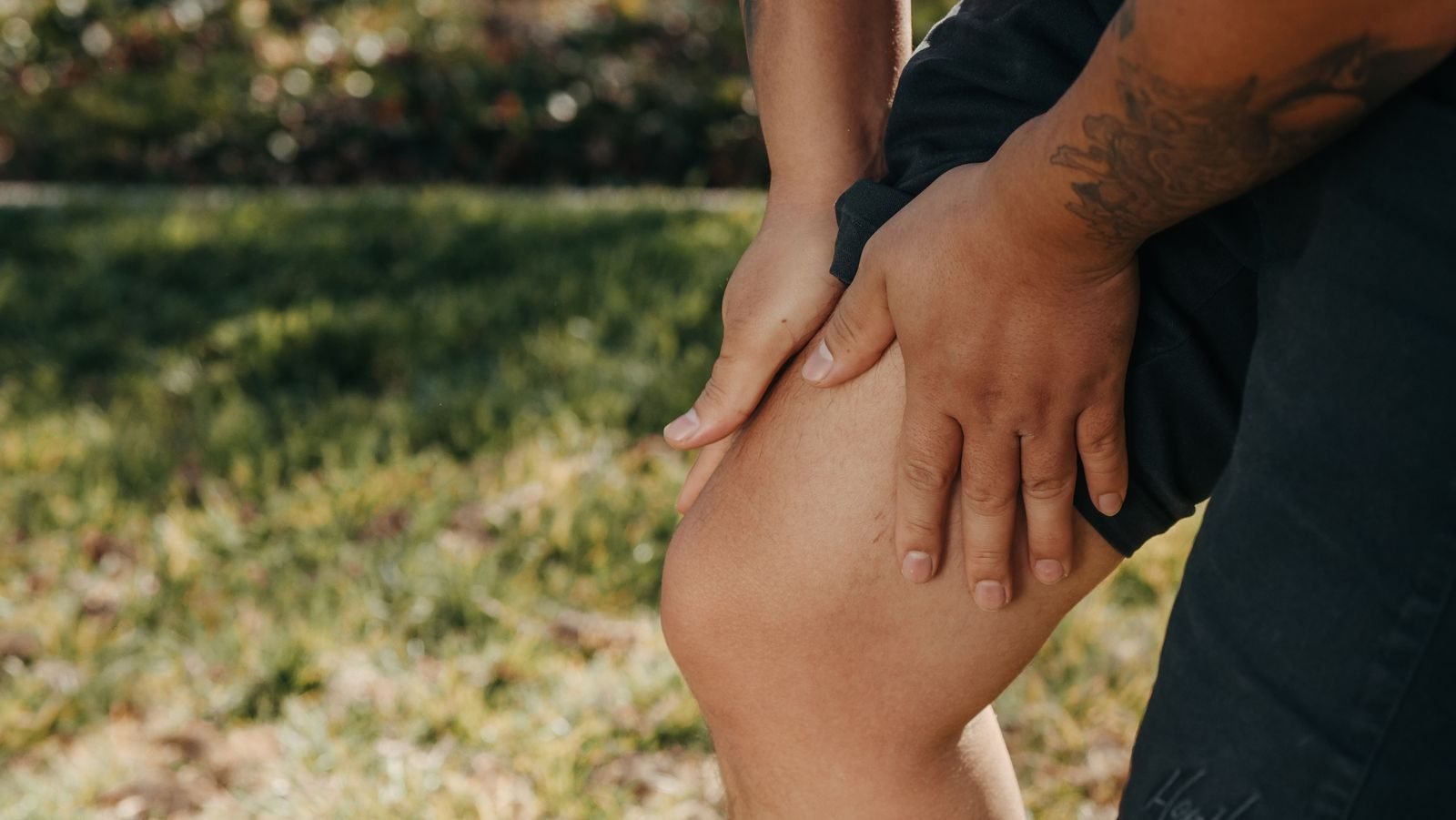 Person holding a painful knee on the grass