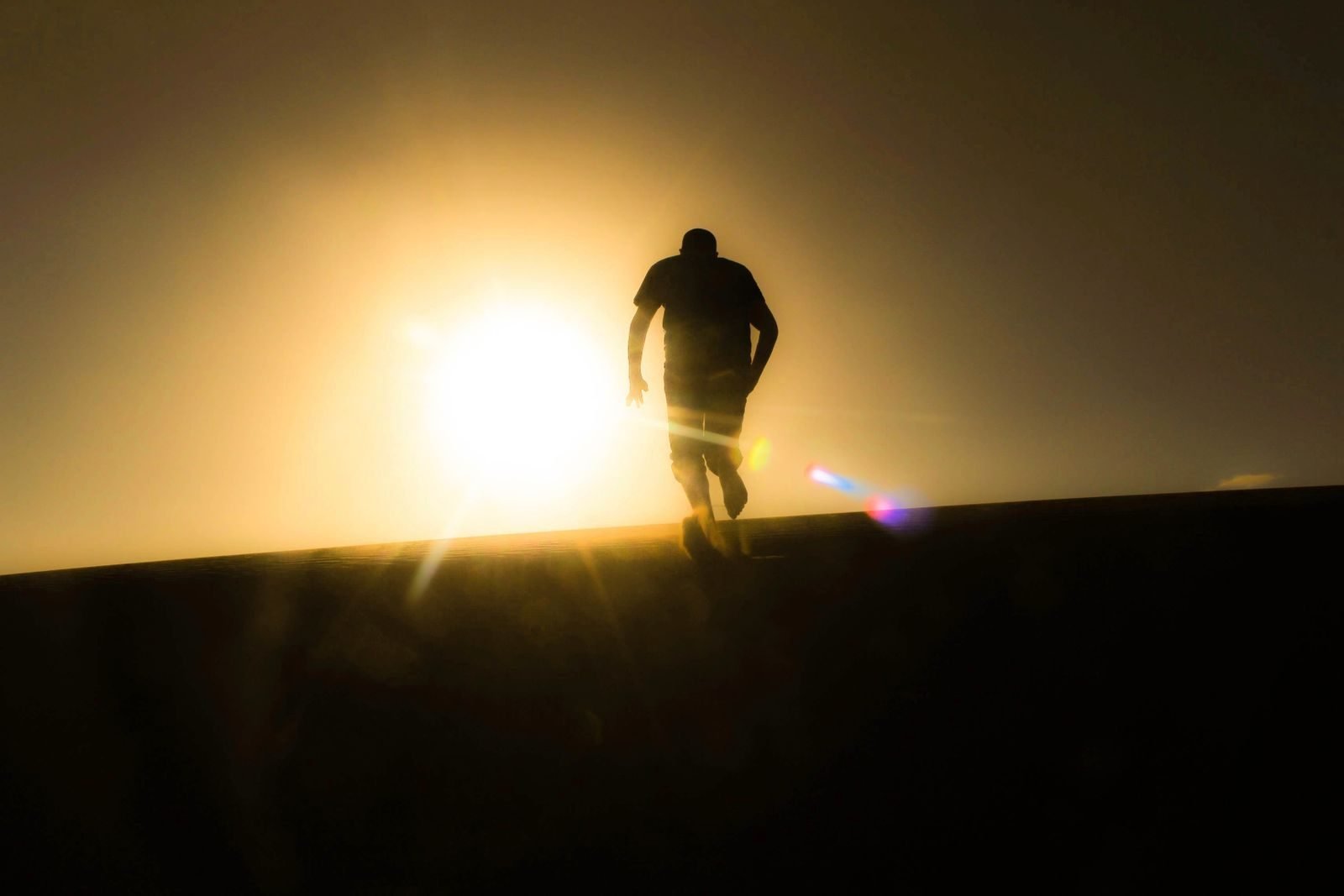 Silhouette of a runner going uphill at sunrise, a test of running durability