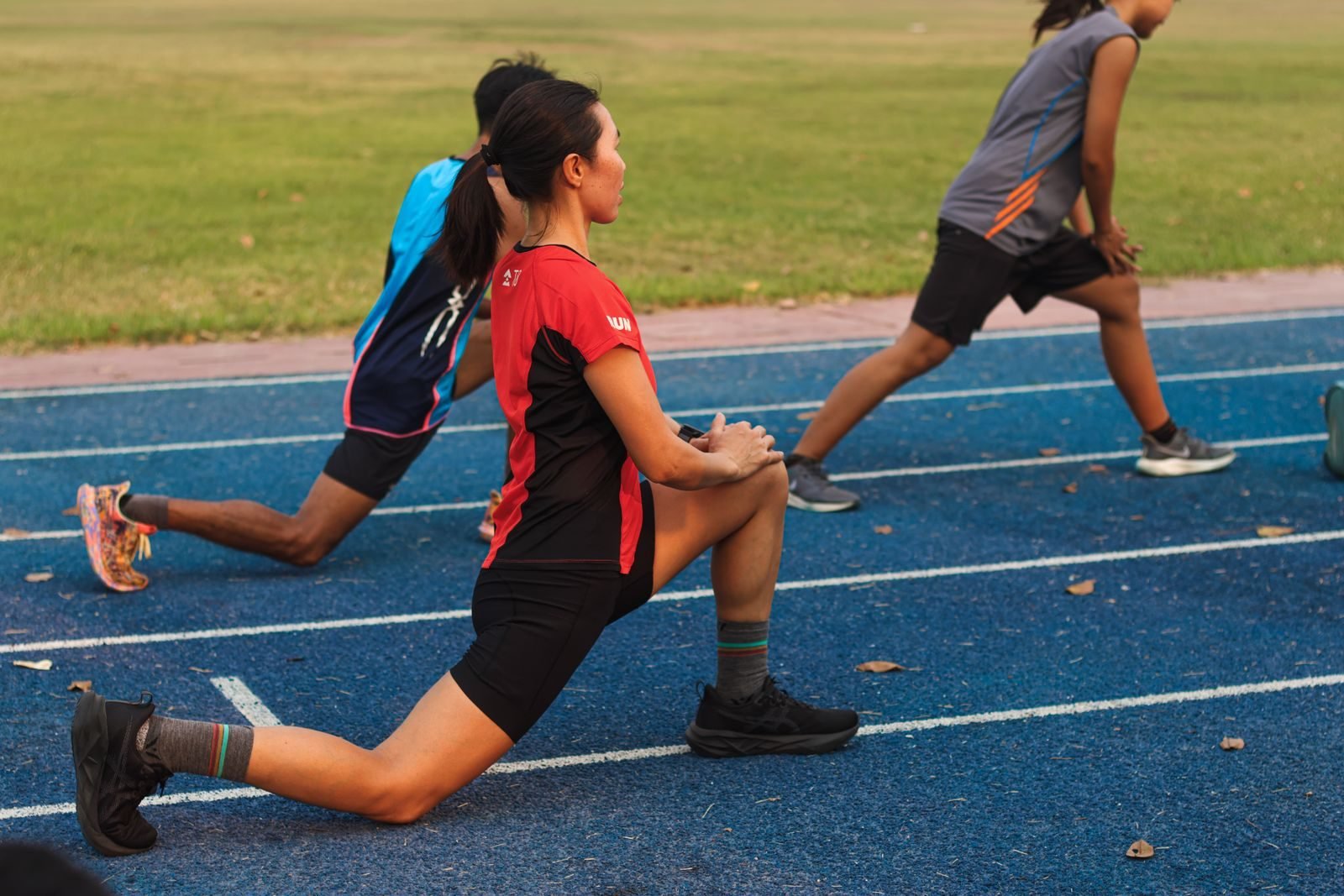 Group of athletes warming up on a track before running form drills