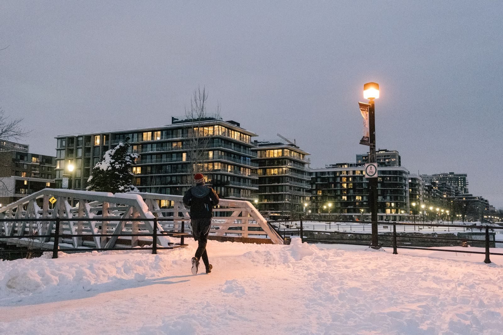 Man running across a snowy bridge at dusk
