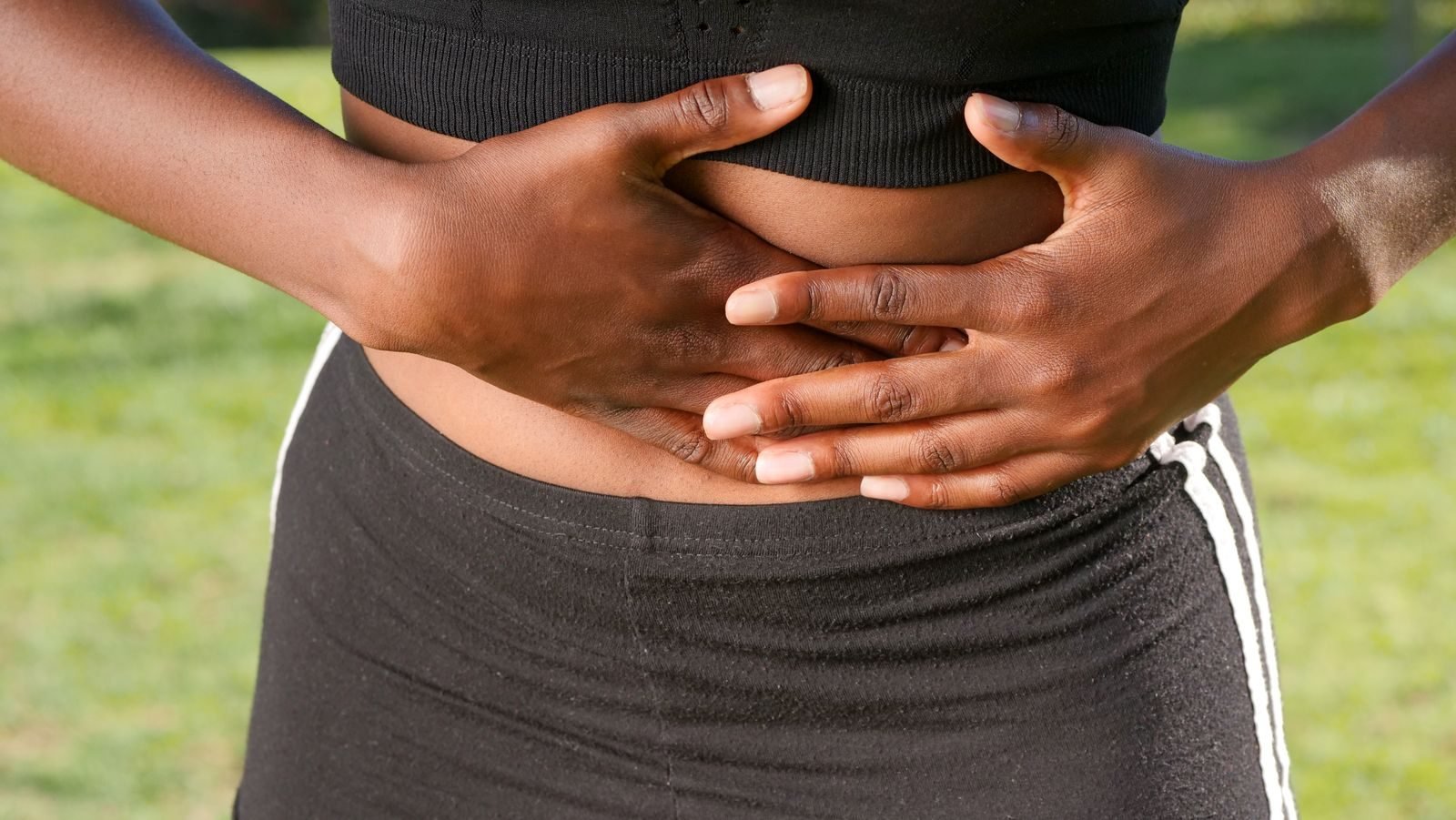 Woman in sportswear holding her side because of a side stitch while running