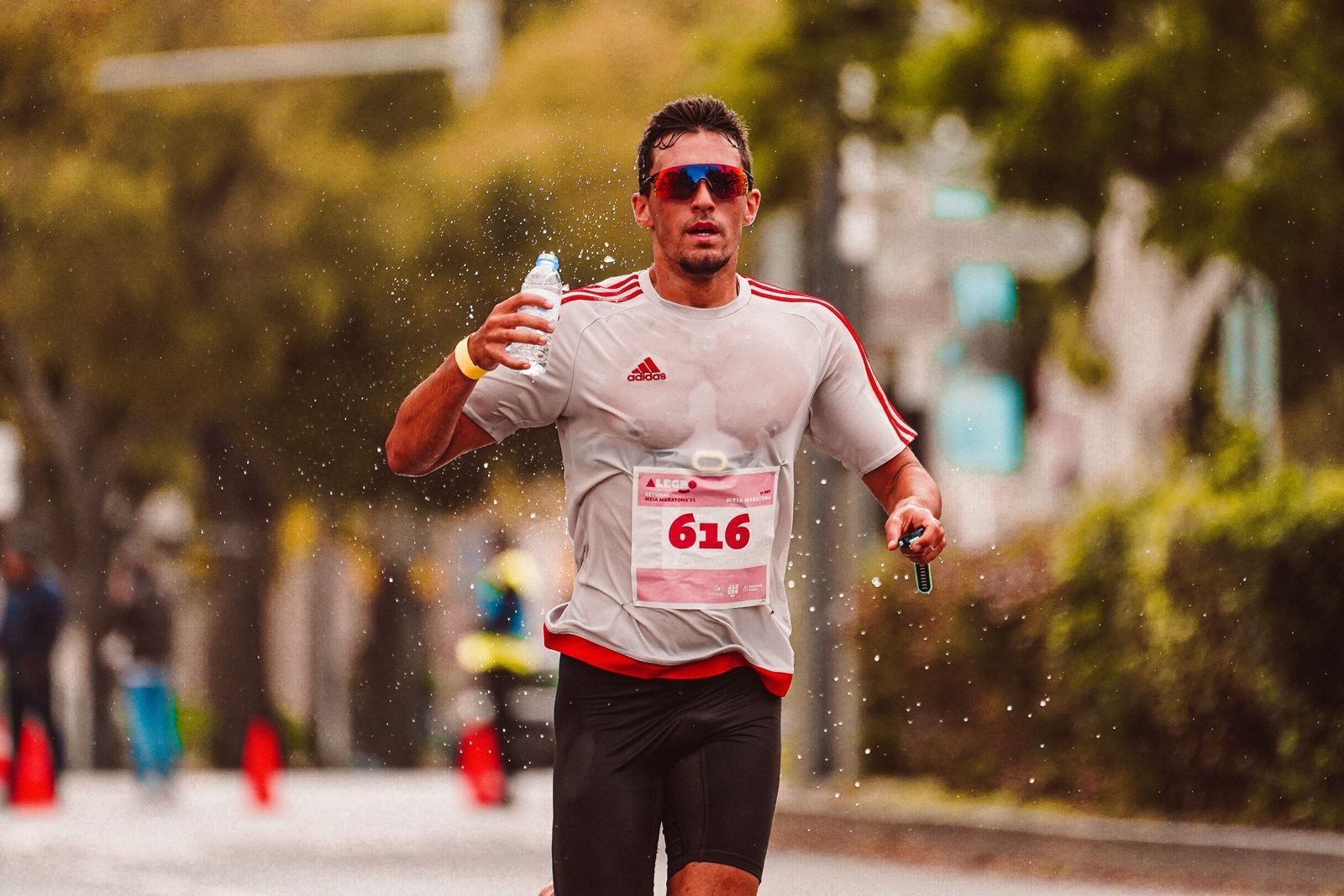 Corredor echándose agua por encima en una carrera con calor, cuando más cuentan la hidratación y electrolitos
