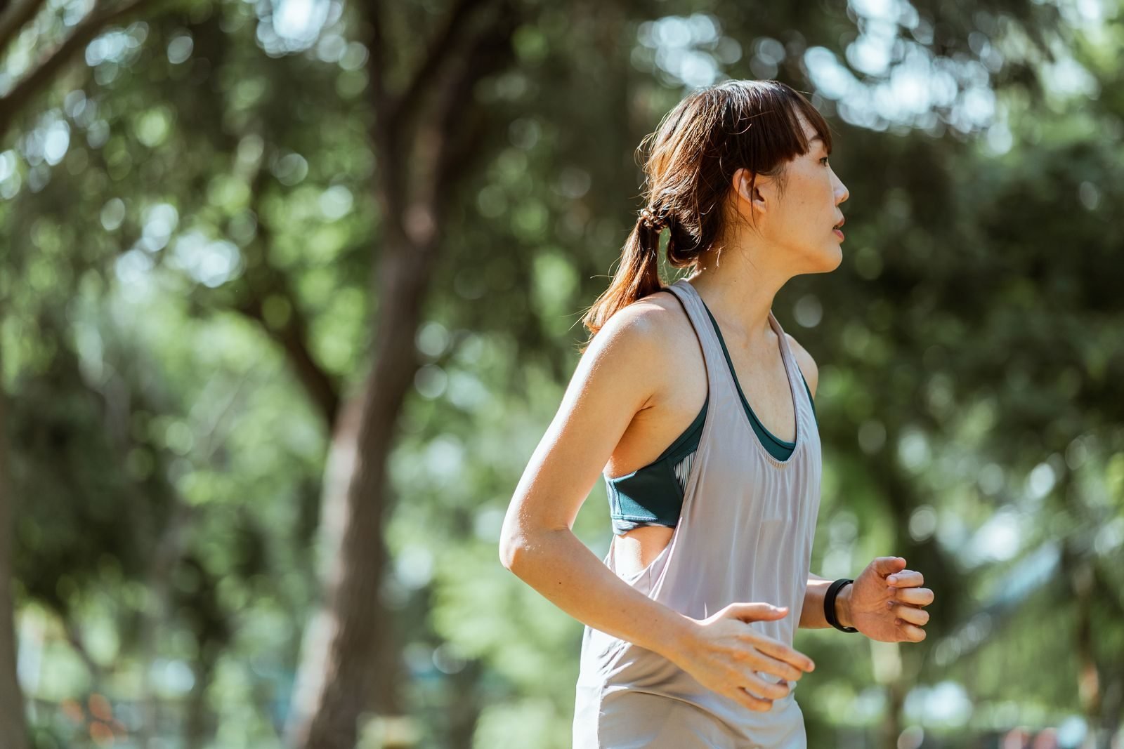 Corredora vista de lado corriendo por un parque con buena técnica de carrera