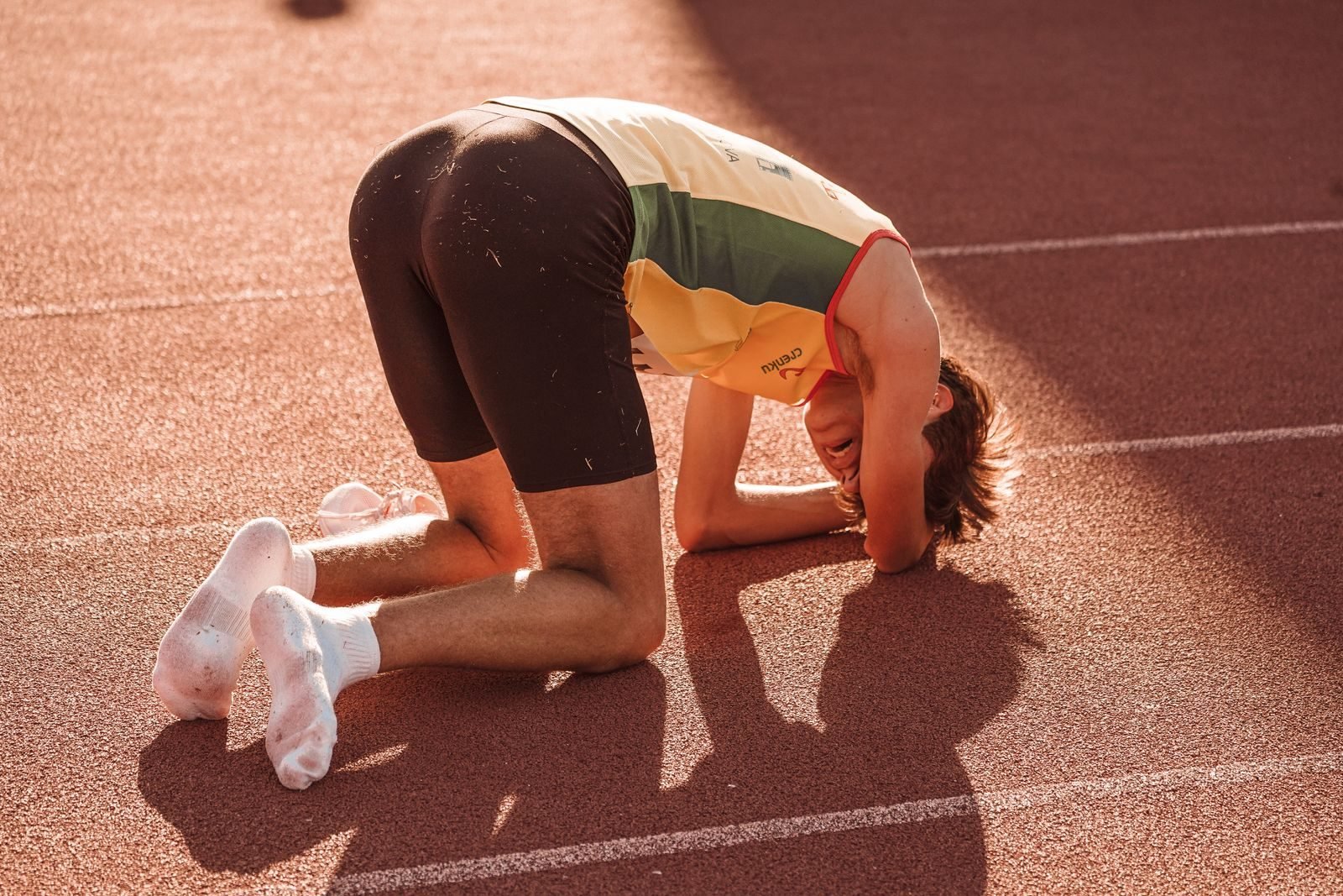 Atleta arrodillado y agotado en la pista tras un test de frecuencia cardíaca máxima