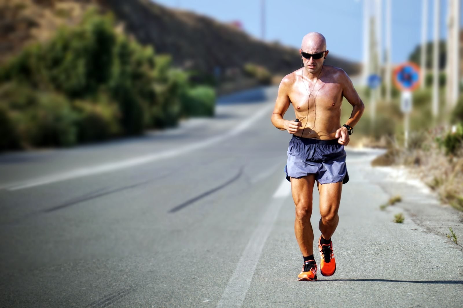 Corredor en una tirada larga por una carretera soleada, entrenando para bajar de 2 horas en media maratón