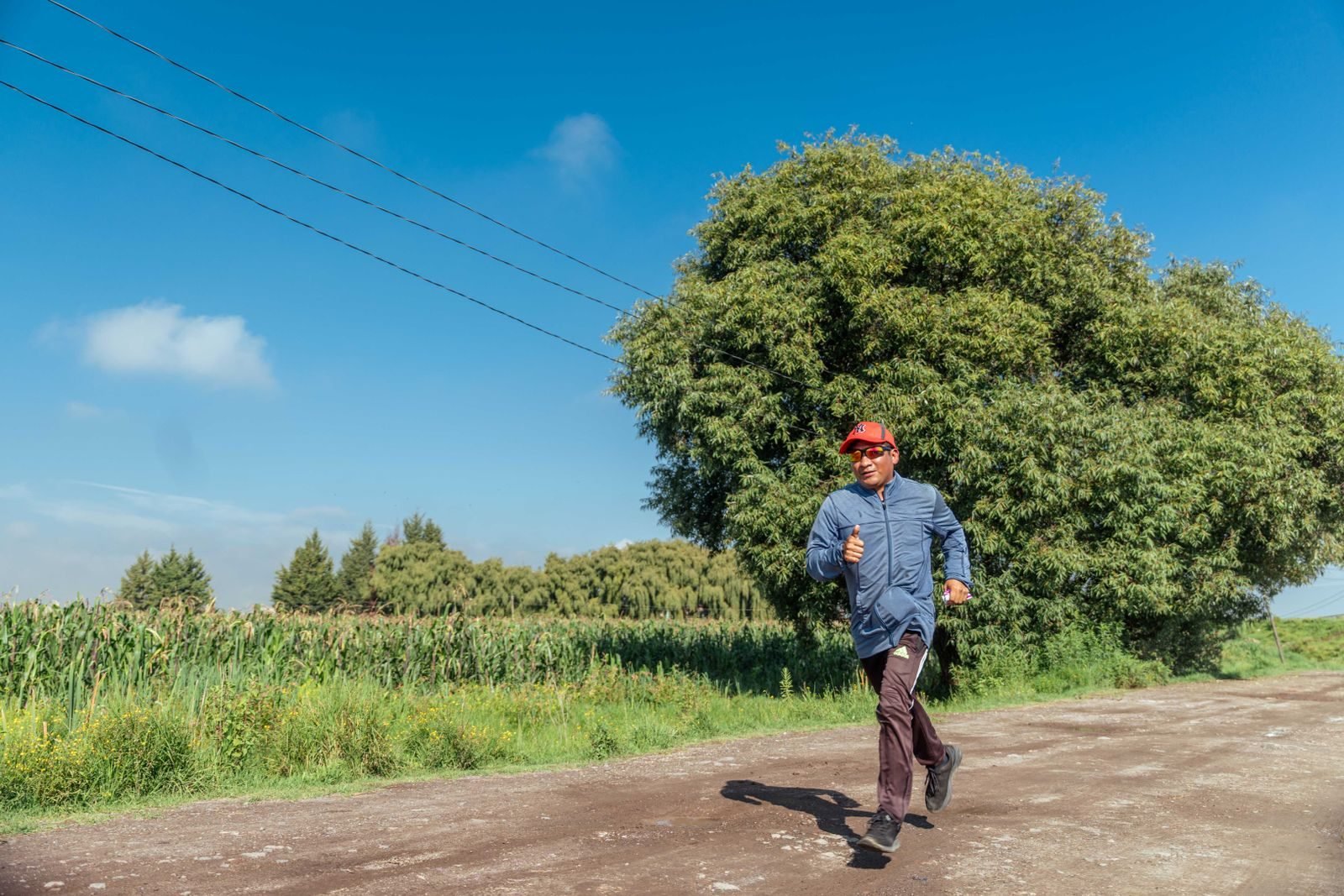 Corredor haciendo una tirada larga por un camino rural bajo el cielo azul