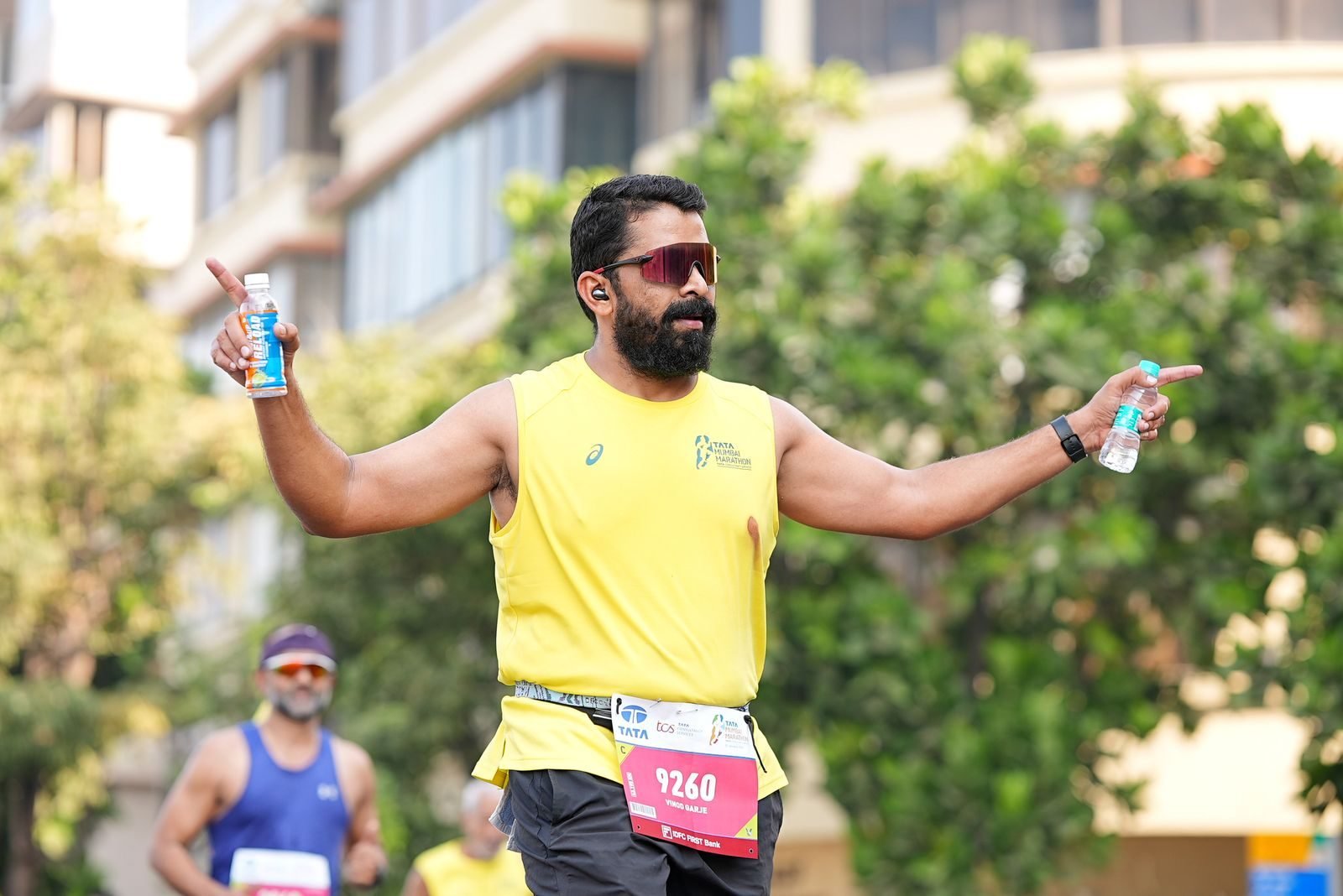 Corredor de maratón con bebida en ambas manos, una práctica para entrenar el intestino en carrera