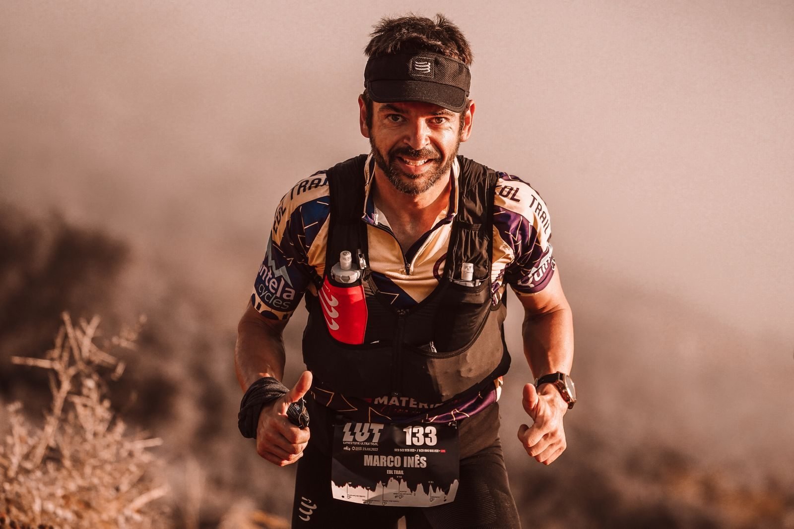 Trail runner with a hydration vest and soft flasks during a mountain race