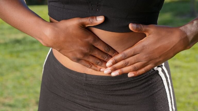 Person outdoors holding their stomach because of digestive discomfort