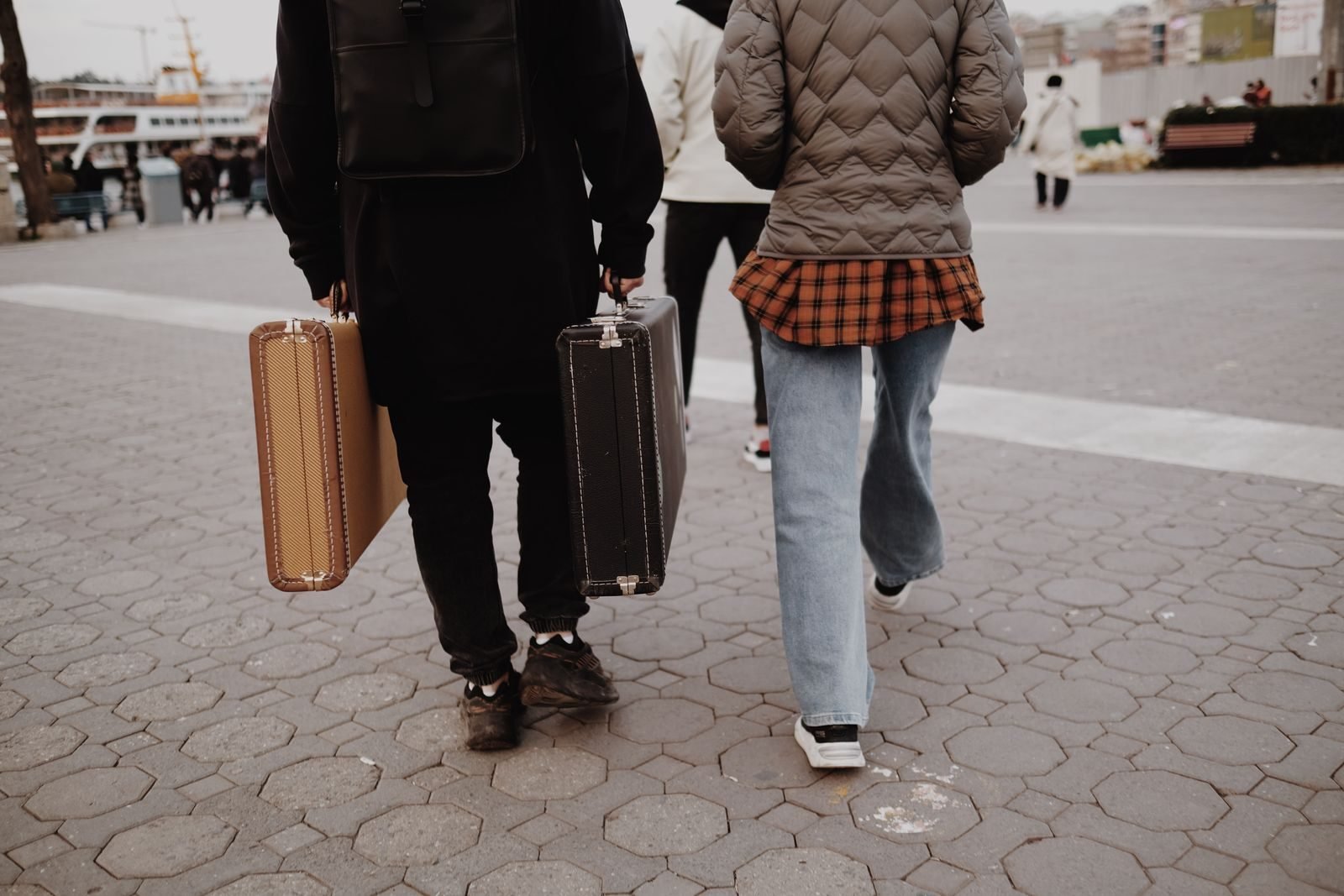 Two travellers walking through a city with suitcases, as when travelling to a race