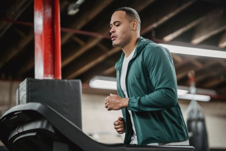 Man running on a gym treadmill seen from the side