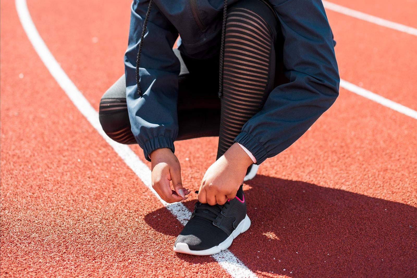 Athlete tying shoes on a running track, cheap gifts for runners