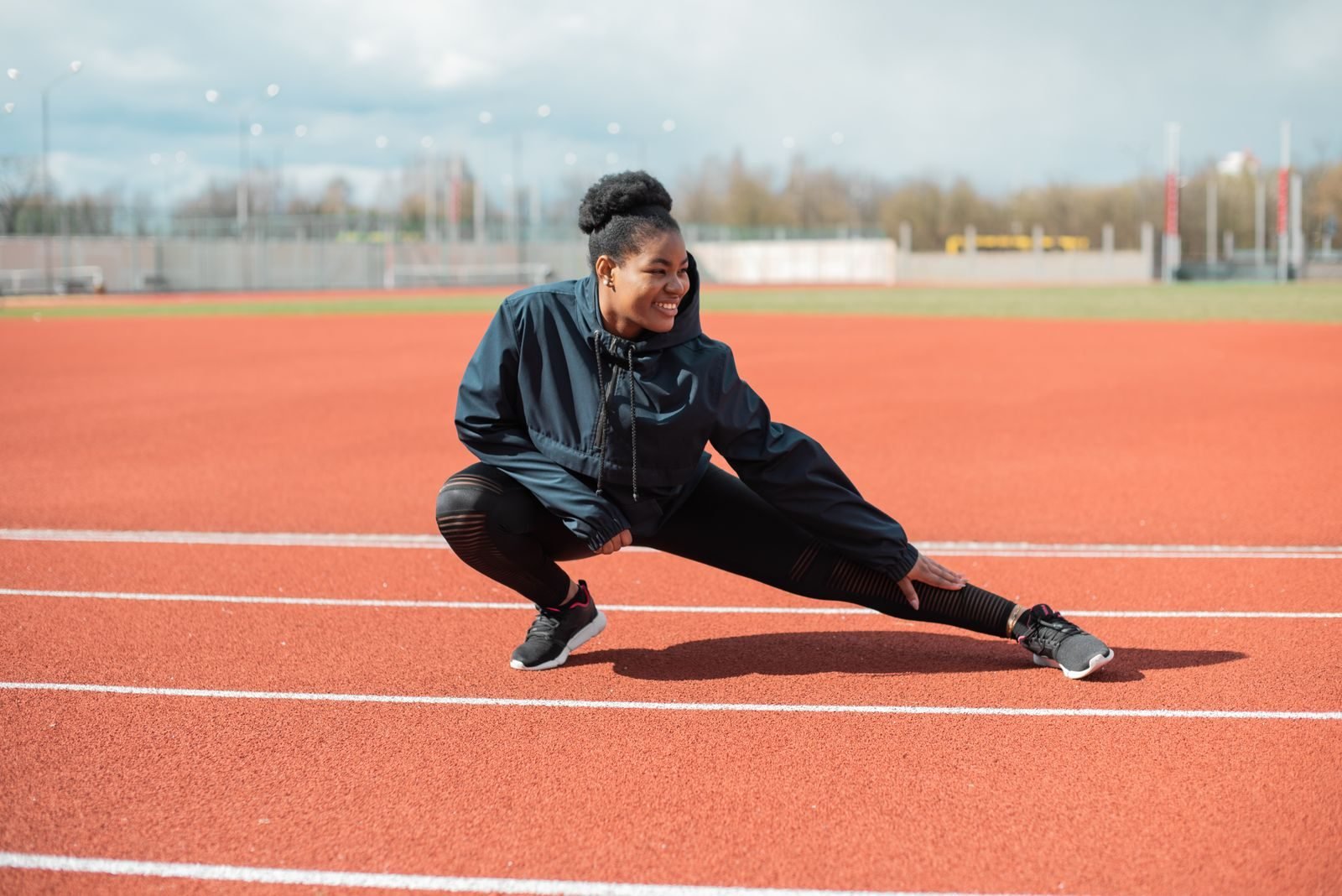Woman stretching on an athletics track as part of her warm up before running