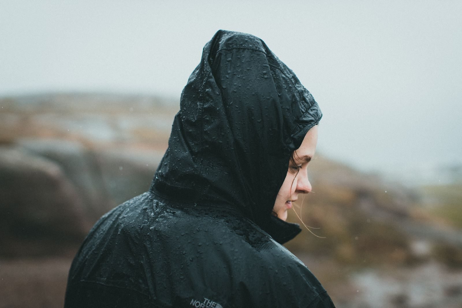 Woman in a hooded waterproof jacket in the rain, part of trail race mandatory gear