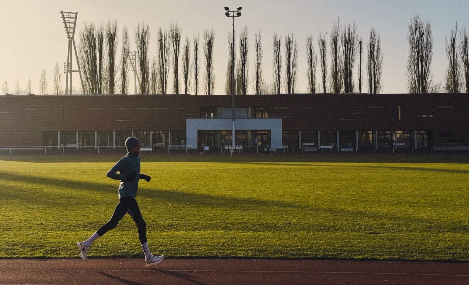 Man running on a track at sunrise to build his weekly running distance