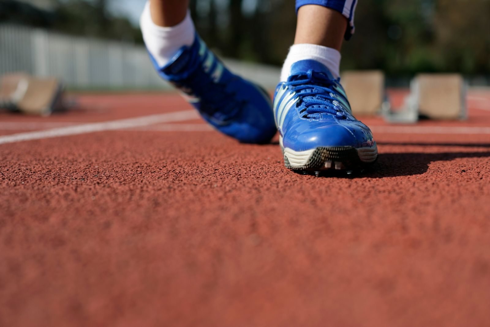 Zapatillas azules de un corredor sobre la pista de atletismo