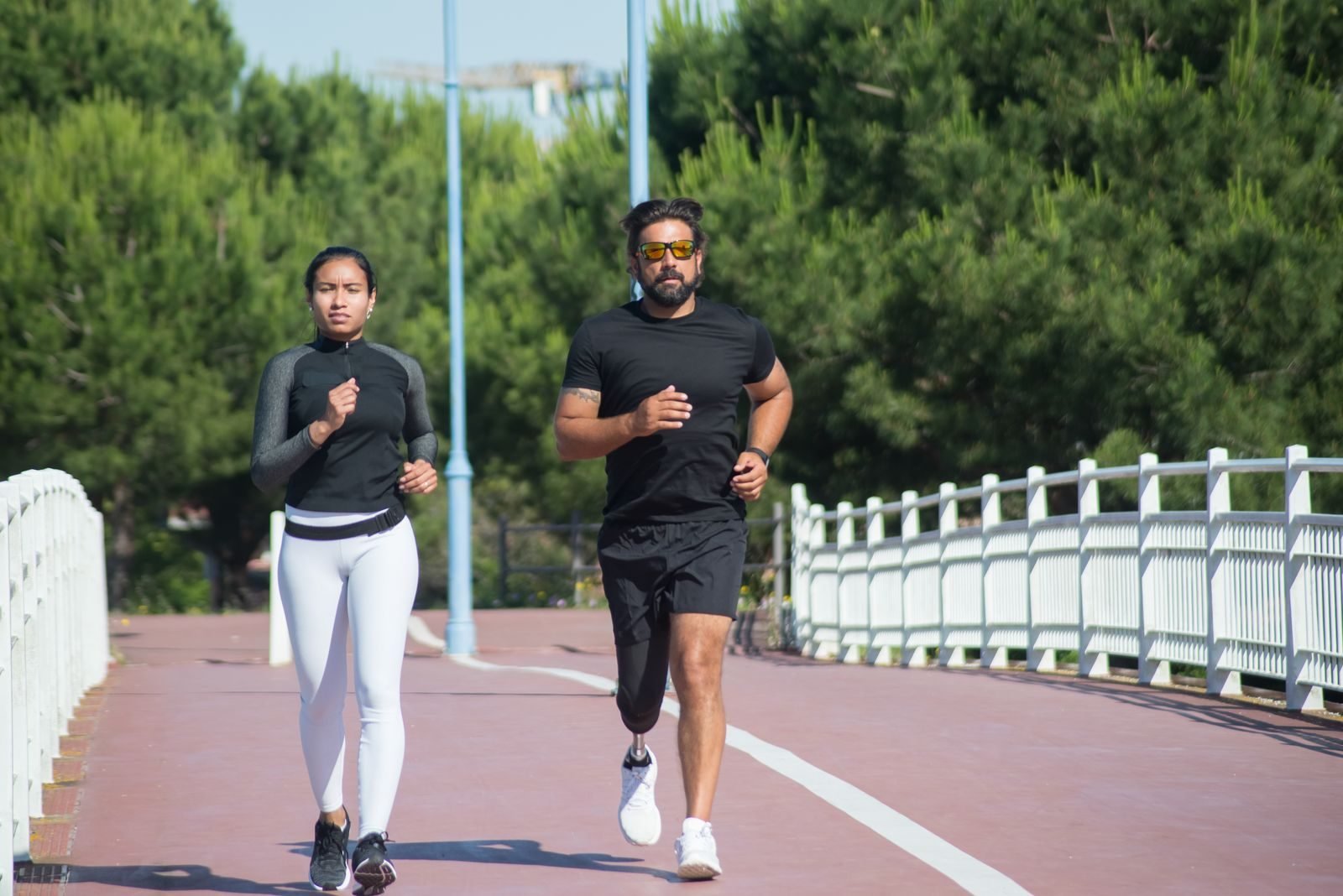 Couple running at an easy pace on a tree-lined path, in zone 2